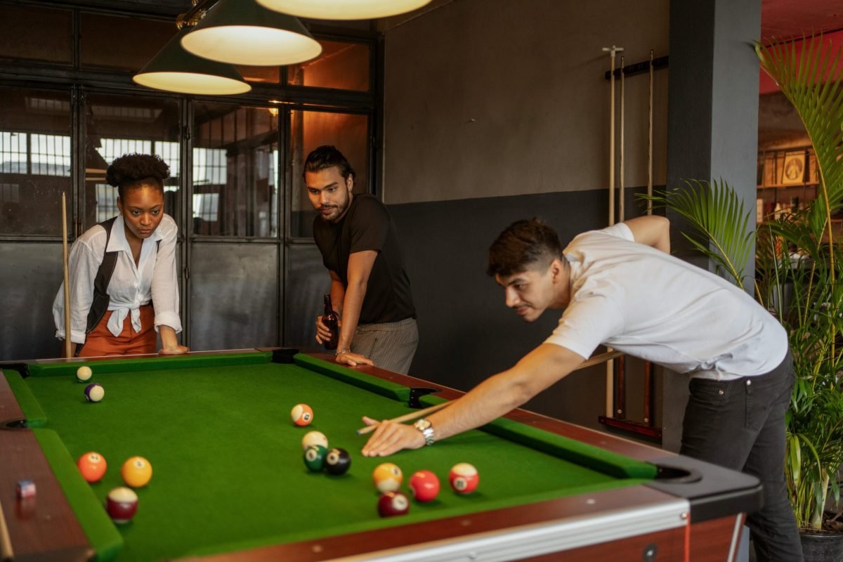 A group of friends playing billiards in a cozy indoor setting, focusing on a strategic shot.