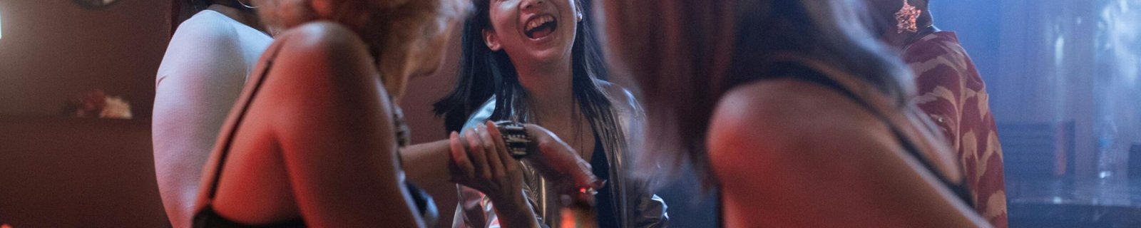 A group of women enjoying a lively night out in a modern bar, filled with laughter and cocktails.